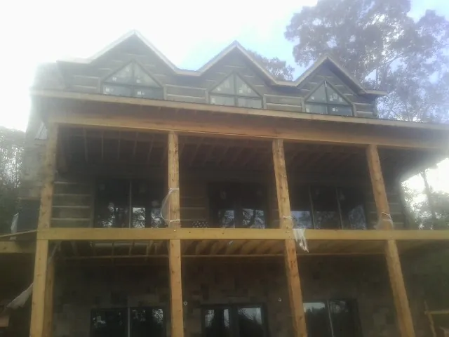 Dormers and porch framing on a large log home under construction — Roof Coating work by our crew in Beaver Dam