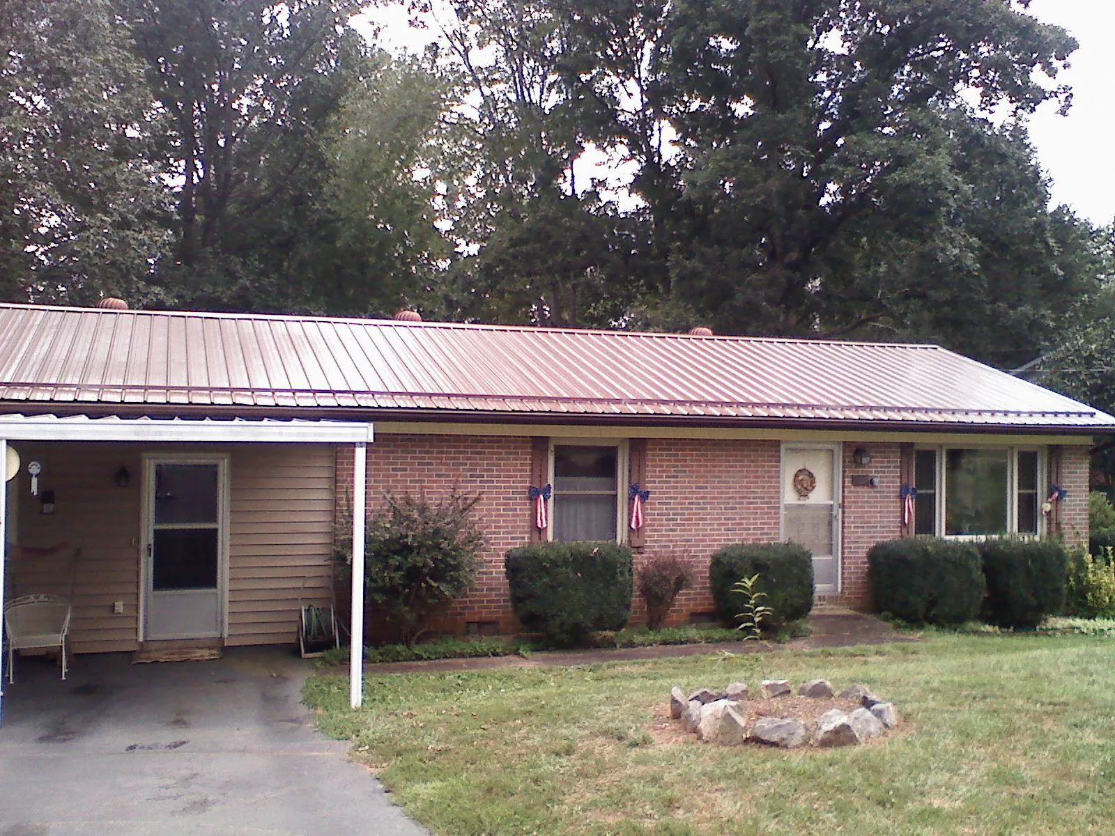 Bronze metal roof and carport on a brick ranch home — Roof Repair work by our crew in Beaver Dam